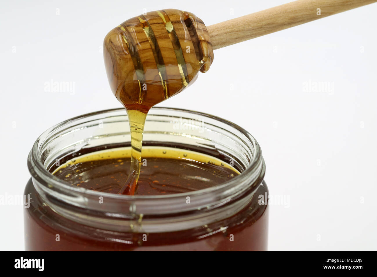 Eine Nahaufnahme von einem honigtopf und ein Löffel Honig auf weißem Hintergrund Stockfoto