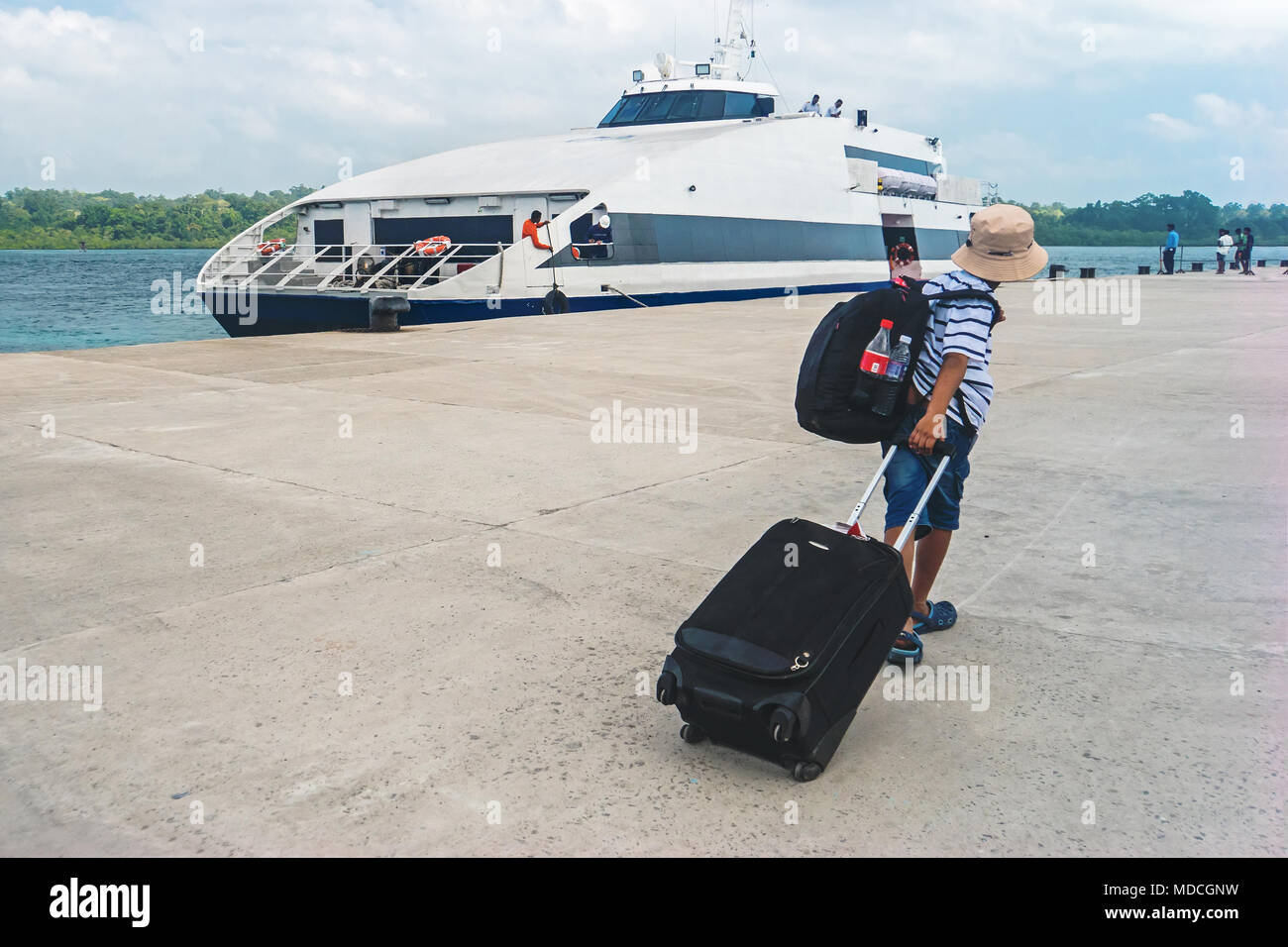 Jungen Kerl Blockierung mit einem Rucksack und Koffer geht in eine Kreuzfahrt auf der Liner. Youngster jugendlich touristische ziehen einen Koffer an Bord der deluxe Schiff eine Stockfoto