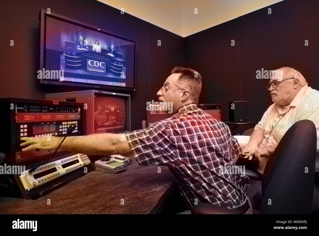 Zwei studio Arbeitnehmer überwachung Fernsehen an Zentren für Krankheitskontrolle (CDC) Abteilung für kreative Dienstleistungen, Roybal Campus, Clifton Road, Atlanta, Georgia, 2005. Mit freundlicher Mitten zur Krankheit-Steuerung. Hinweis: Das Bild hat digital über ein modernes Prozess eingefärbt worden. Farben können nicht wissenschaftlich korrekt sein. () Stockfoto