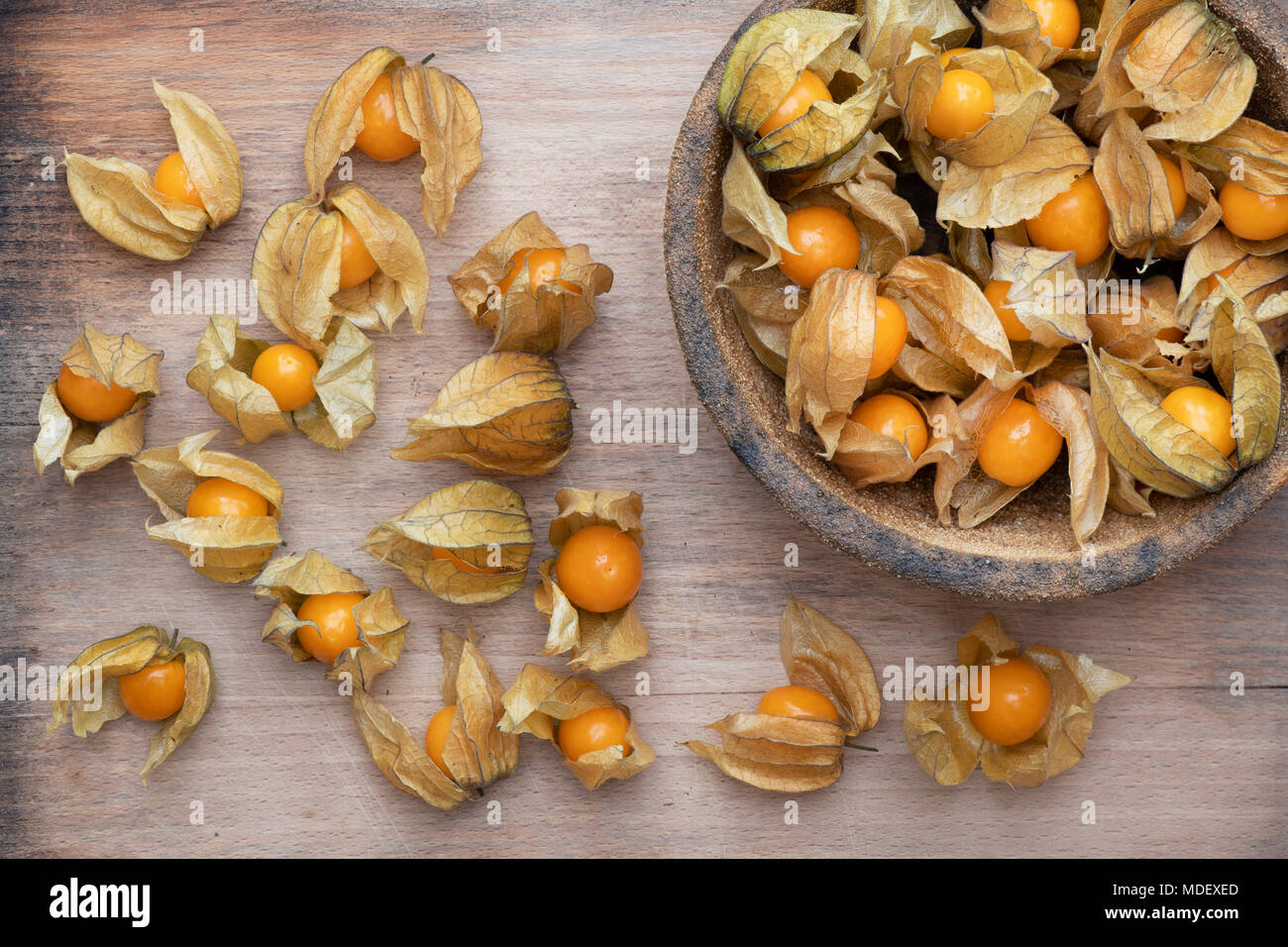 Physalis rubro. Kap Stachelbeeren Obst in einer Schüssel auf einem Holzbrett Stockfoto