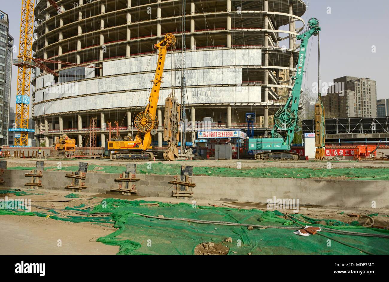 Piling Maschinen vor einem ovalen Gebäude Form auf einer Baustelle im Osten von Beijing, China, Stockfoto
