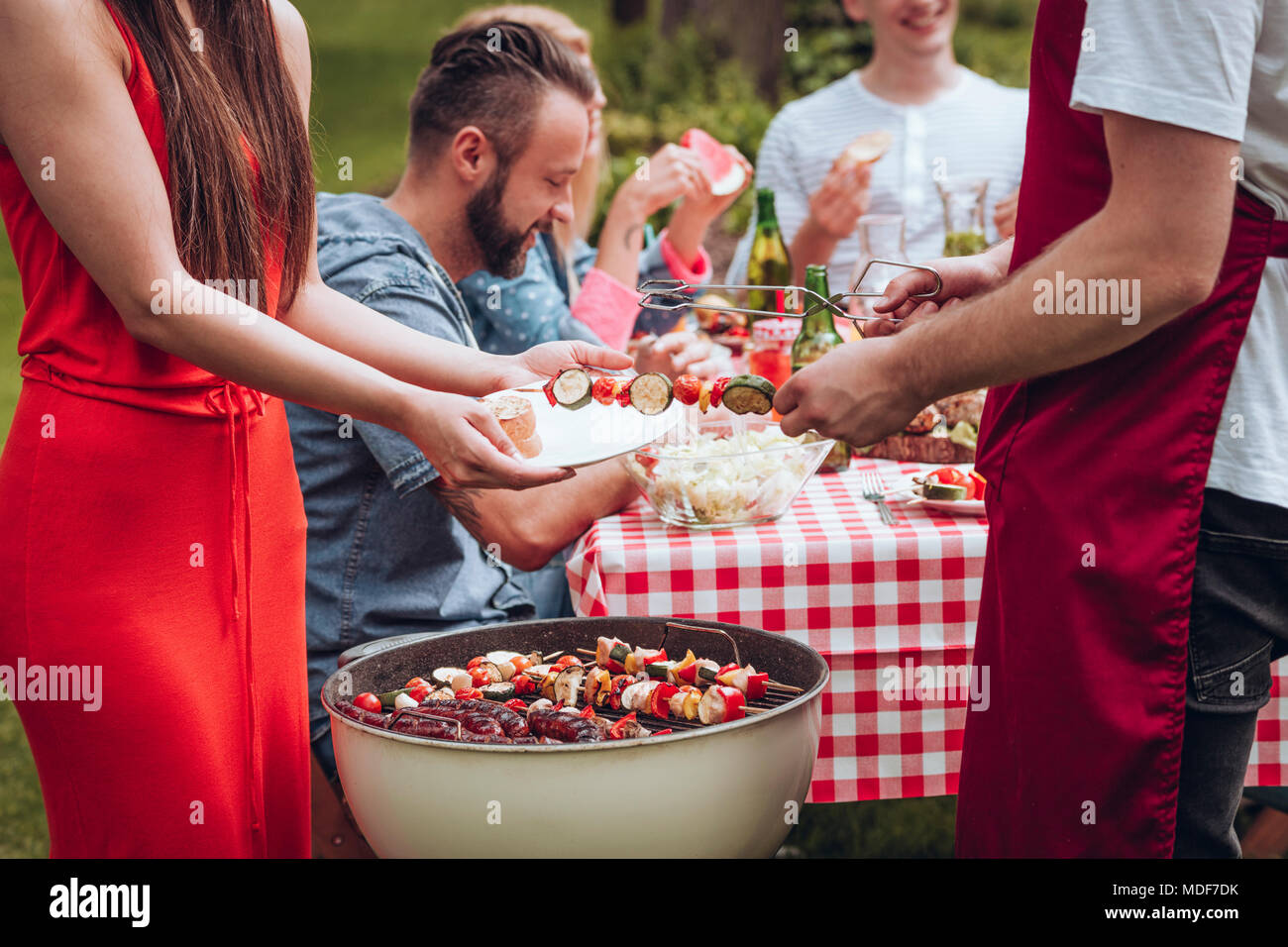 Mann in eine Schürze mit shashliks an einen Freund während einer Grillparty Stockfoto
