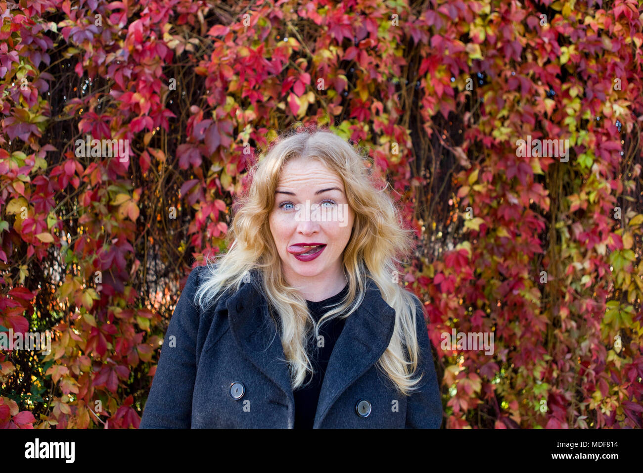 Die junge blonde Frau zeigt die Zunge Stockfoto