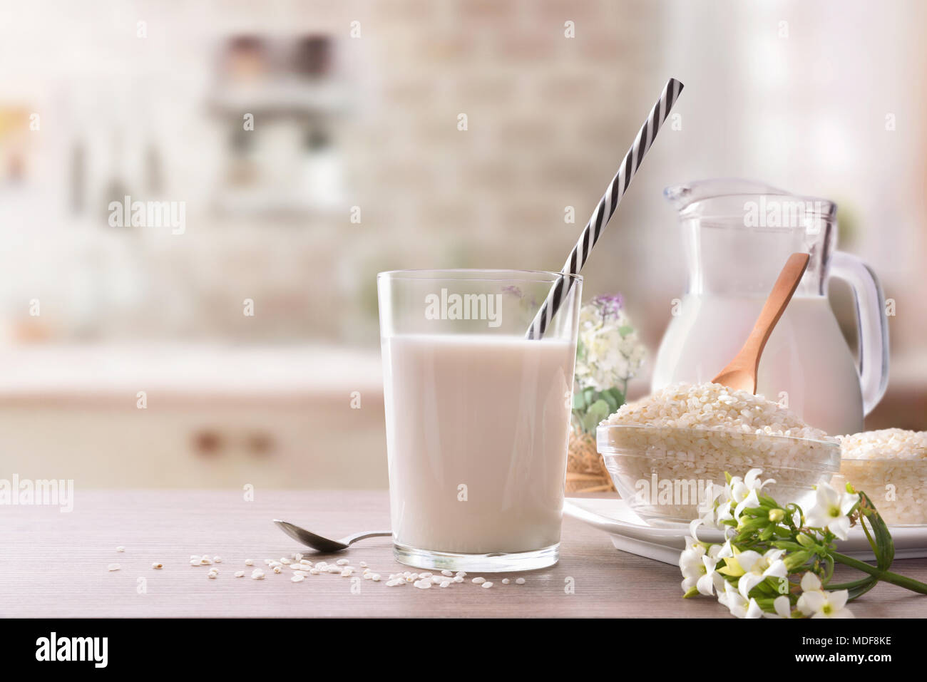 Reis Milch und Reis im Behälter auf einem Holztisch in rustikale Küche. Alternative Milch. Vorderansicht. Horizontale Zusammensetzung Stockfoto