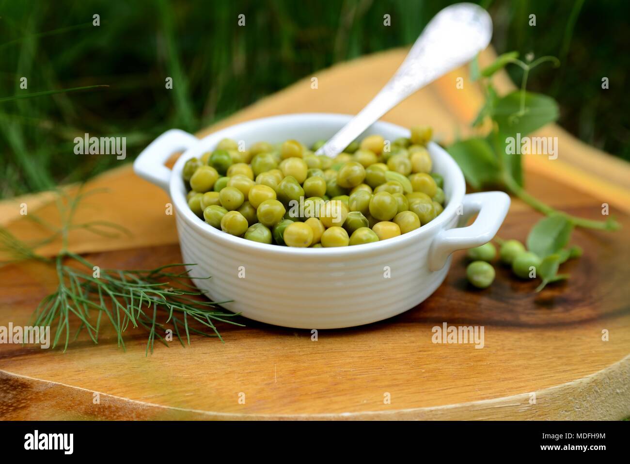 Gekochte junge grüne Erbsen in einer weißen Schüssel. Stockfoto