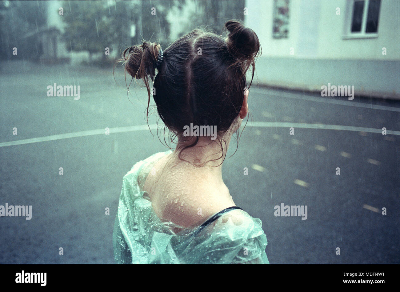 Ansicht der Rückseite ein junges Mädchen mit einem doppelten oberen Knoten im Regen stehen Stockfoto