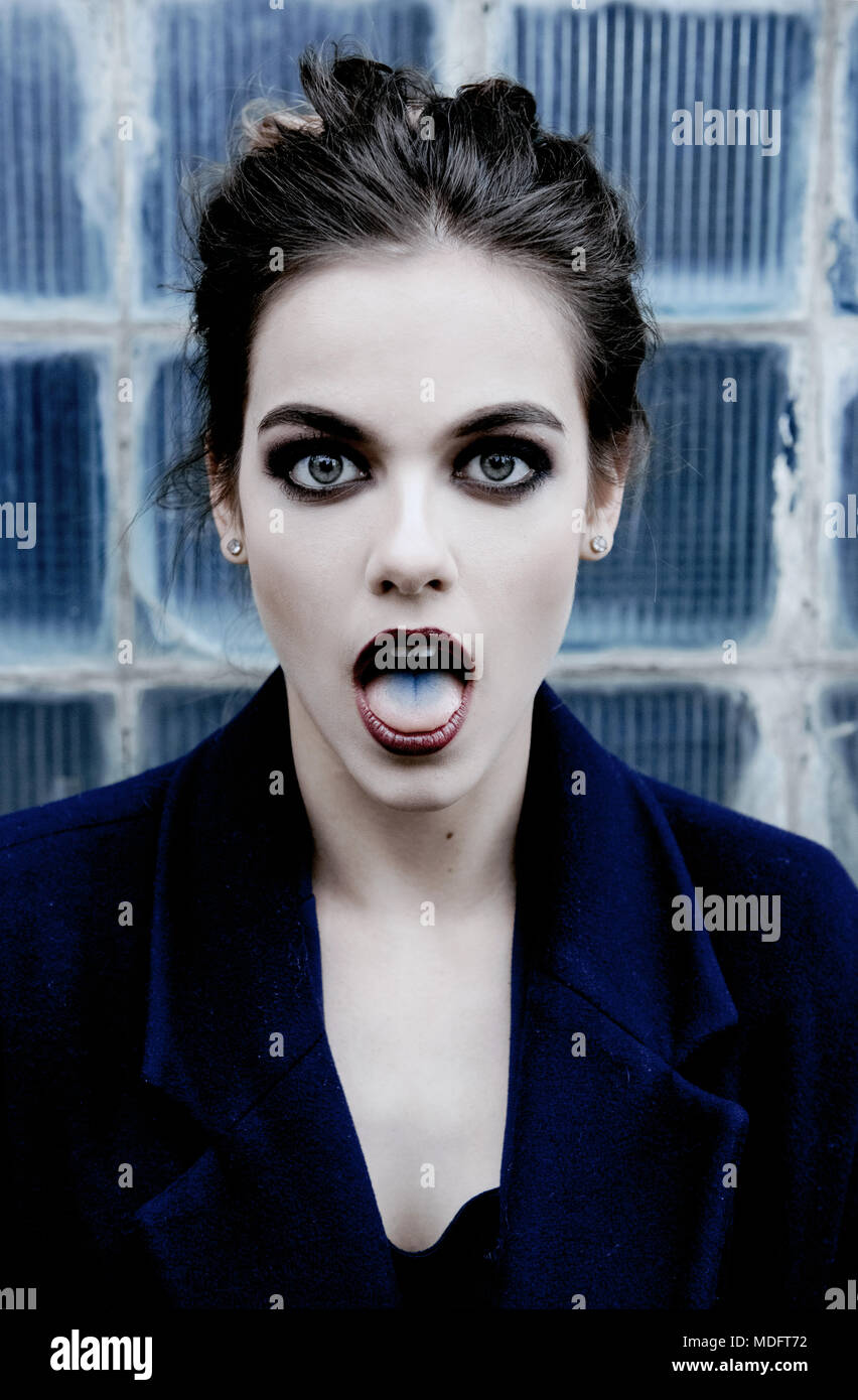 Portrait einer Kantigen junge Frau mit Ihrem Mund offen zeigen eine Blaue Zunge Stockfoto
