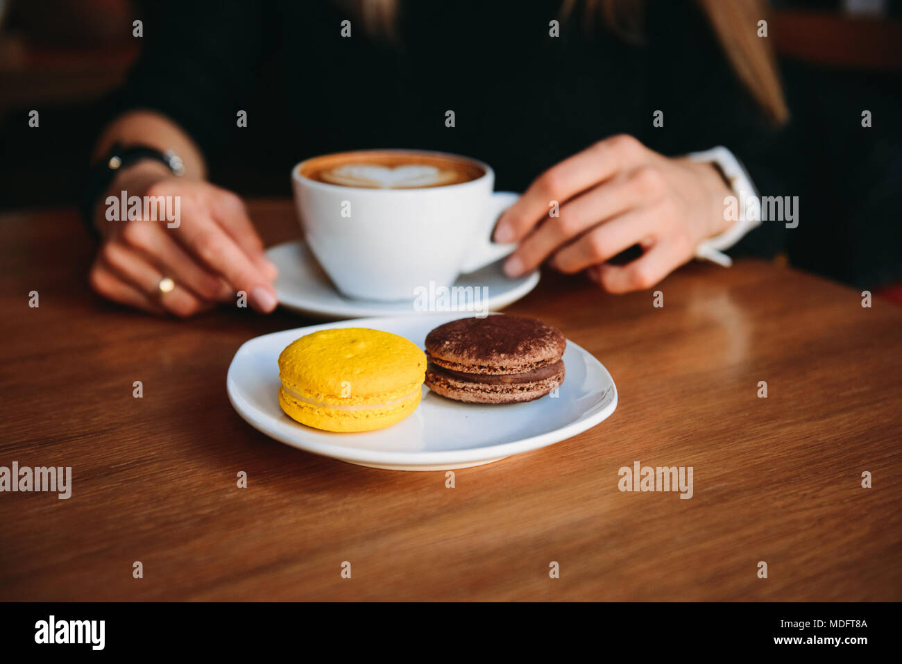 Frau genießen eine Tasse Kaffee und Makronen Stockfoto