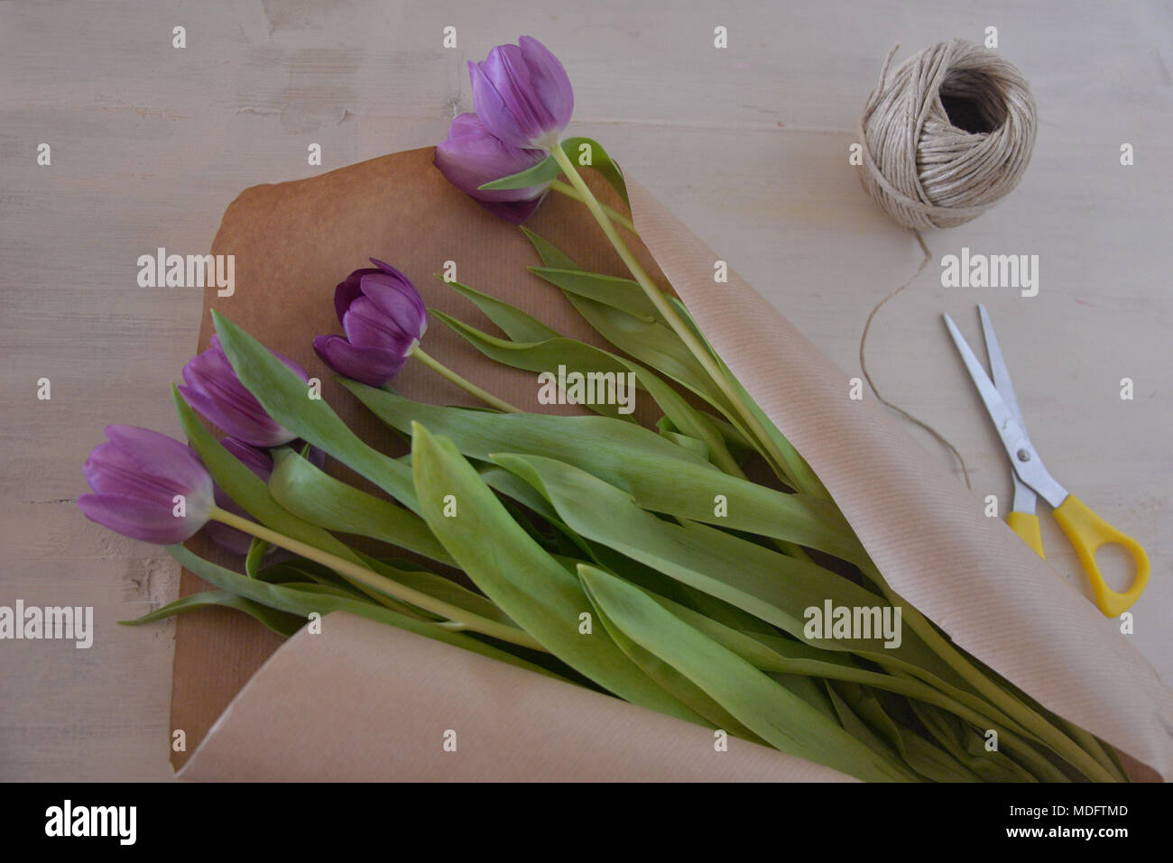 Blumenstrauß aus Tulpen, braunem Papier, Schnur und Schere Stockfoto