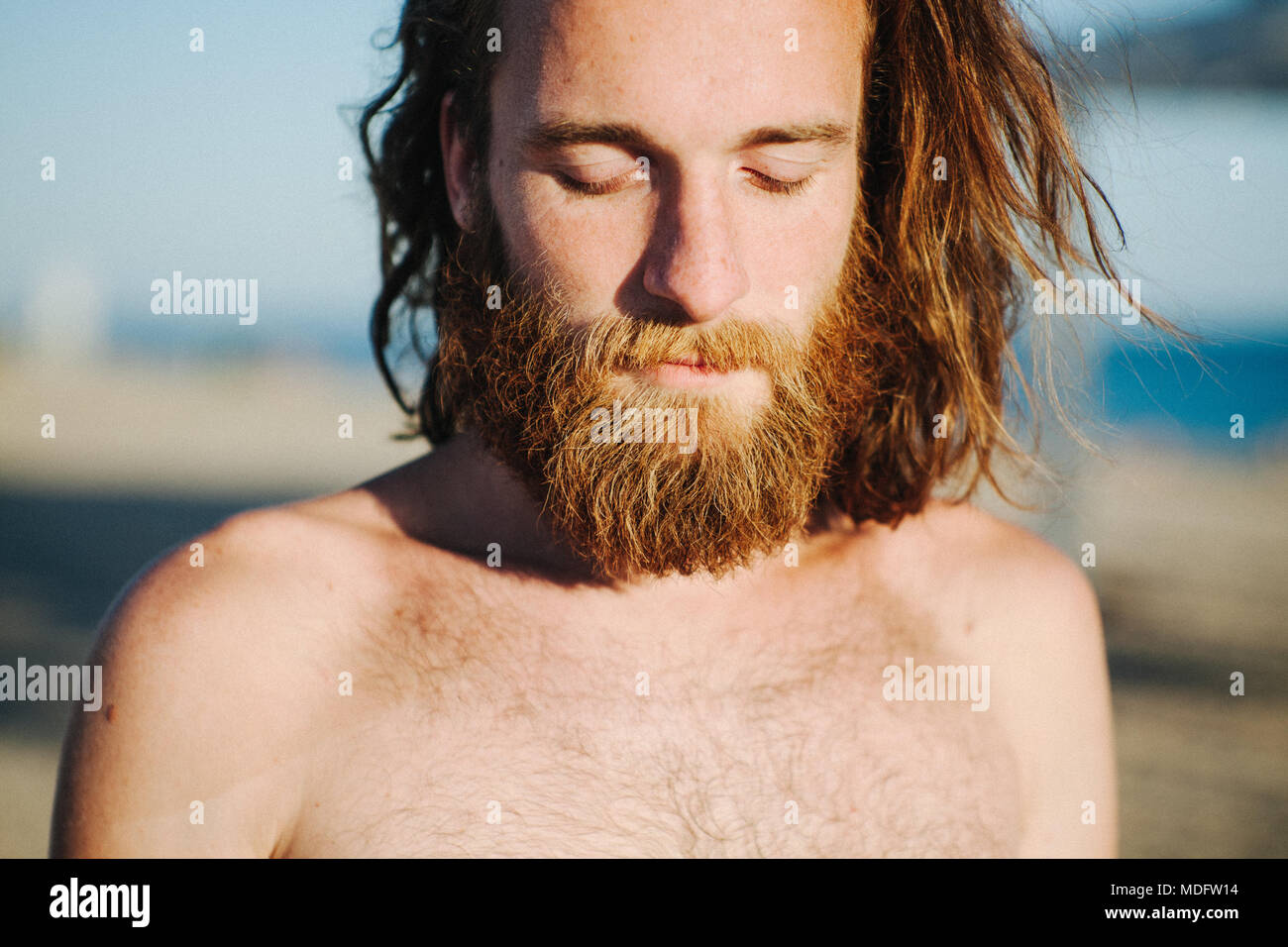 Porträt eines Mannes mit langem Haar und Bart stehen am Strand. Stockfoto