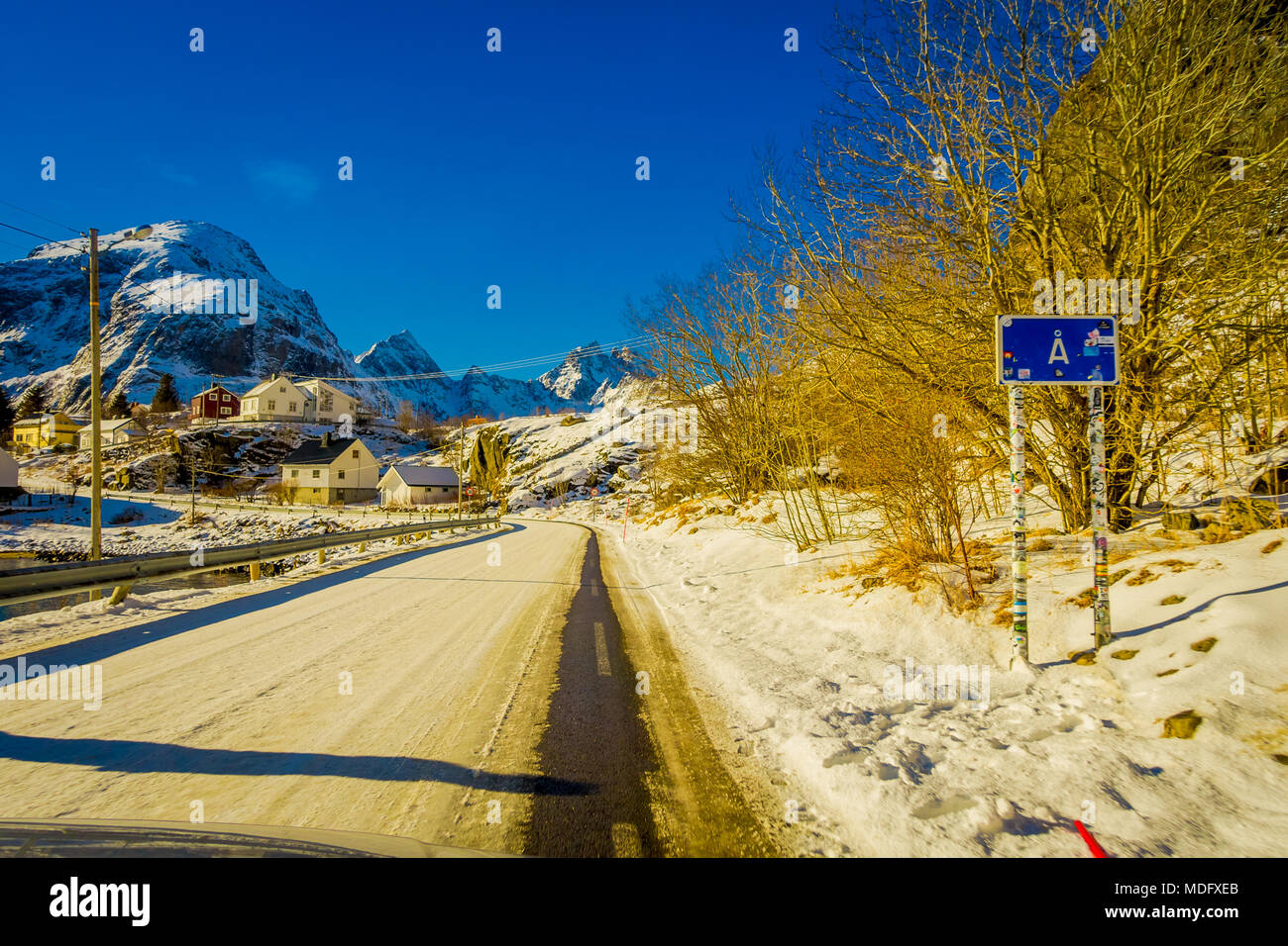 Henningsvær, Norwegen - 04 April, 2018: Im freien Blick auf informative Zeichen mit Holzhäusern auf der einen Seite der Strasse mit Schnee eines typischen kleinen Dorf in Lofoten abgedeckt Stockfoto