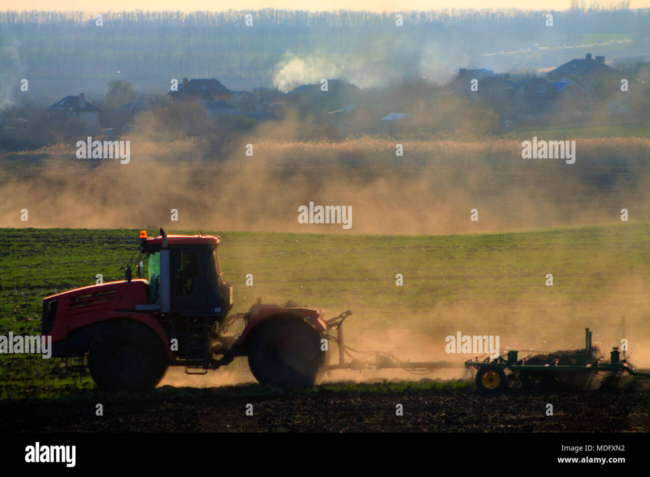Bauer auf einem leistungsfähigen Traktor pflegt das Feld im Frühling vor dem Einpflanzen von Weizen Stockfoto