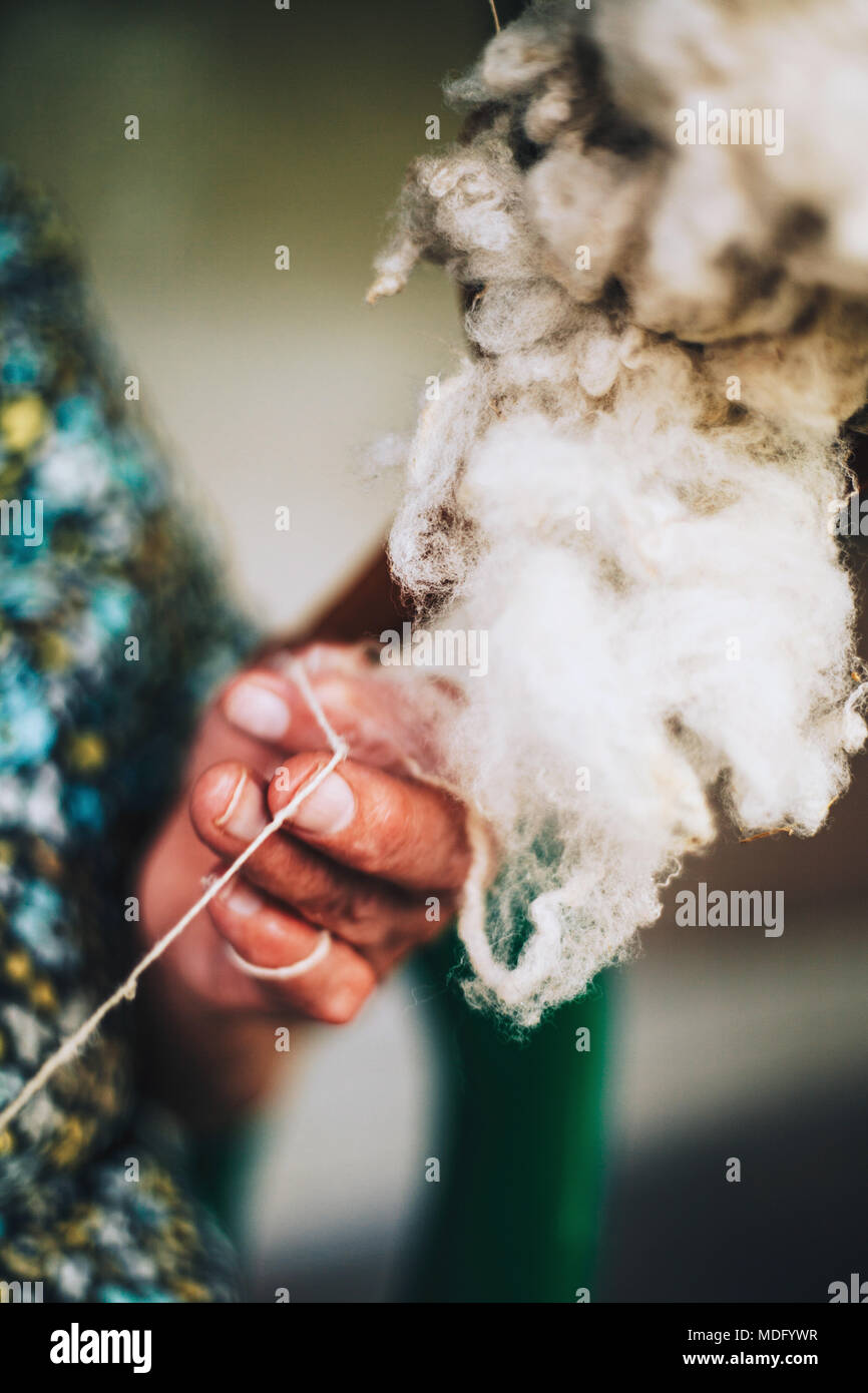 Nahaufnahme der Finger einer alten Frau ist die Garne zum Stricken von natürlichen groben Schafwolle (natürliche Faser) auf traditionelle Art und Weise Stockfoto