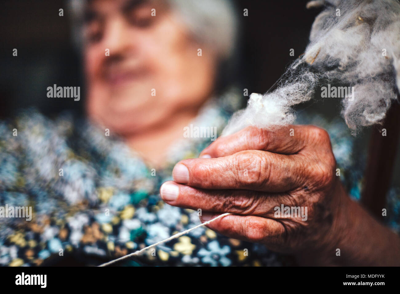 Nahaufnahme der Finger einer alten Frau ist die Garne zum Stricken von natürlichen groben Schafwolle (natürliche Faser) auf traditionelle Art und Weise Stockfoto