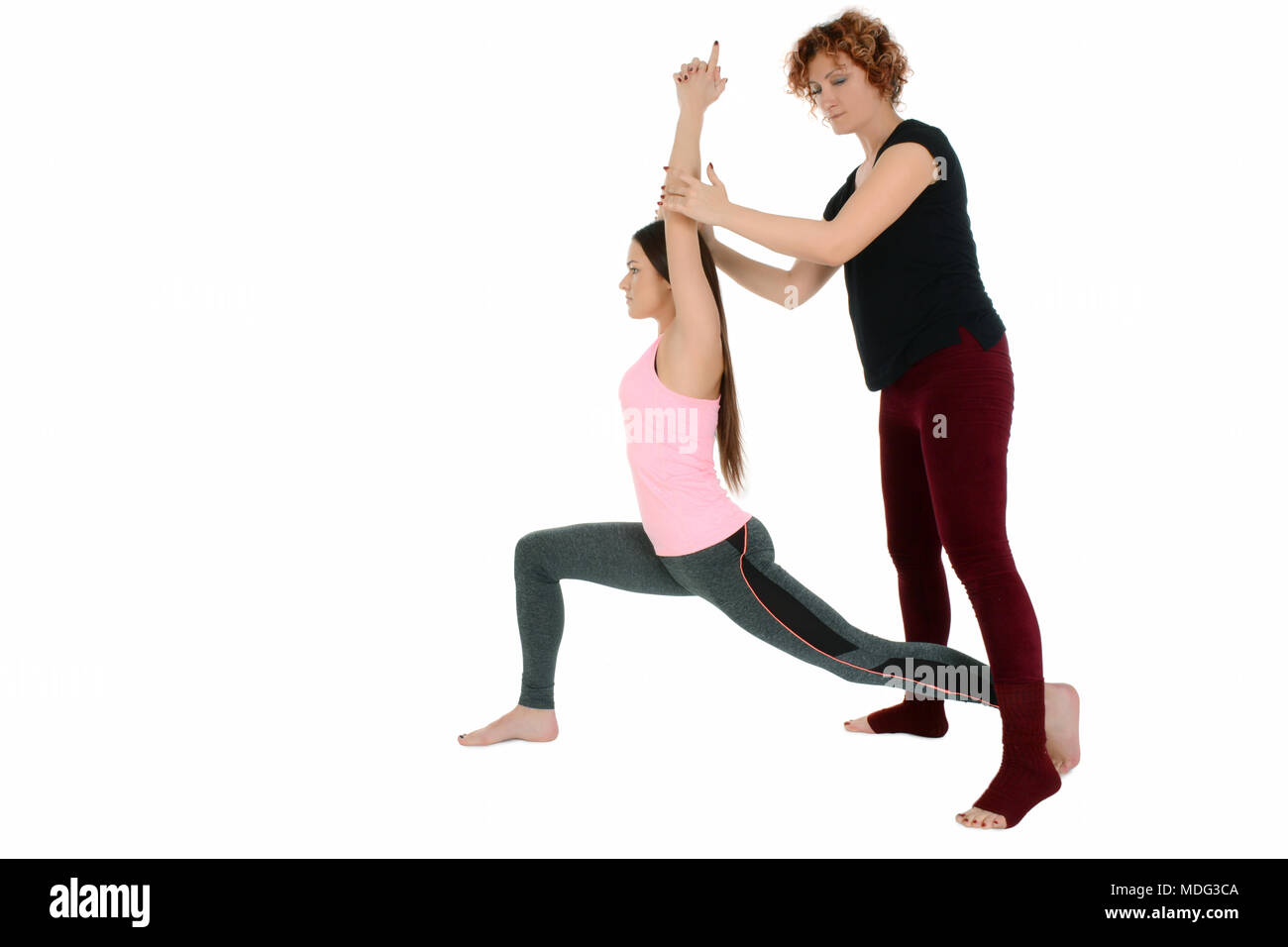 Yoga Lehrerin zeigt, wie eine junge weiße Mädchen im Yoga position Krieger darstellen, und auf Sanskrit Virabradasana. Stockfoto