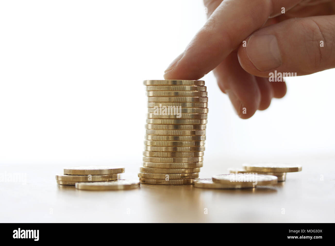 Hand mehr Goldmünzen um Geld auf weißem Hintergrund. Nahaufnahme der Hand eine Münze von Münzen zu stapeln. Wirtschaft Finanzen und Geld Konzept Stockfoto