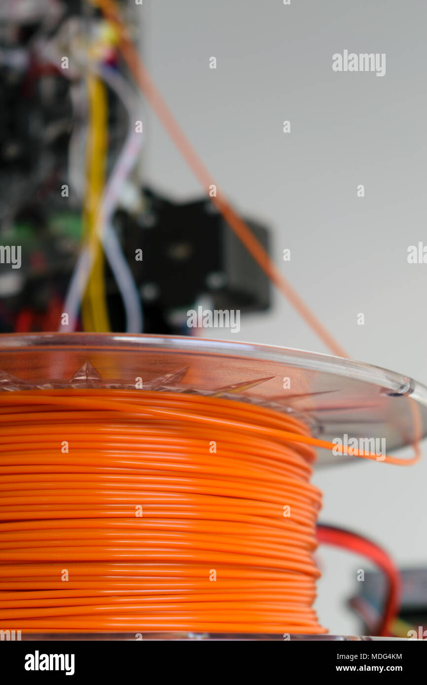 3d-Drucker orange Filament mit Drucker im Hintergrund Stockfoto