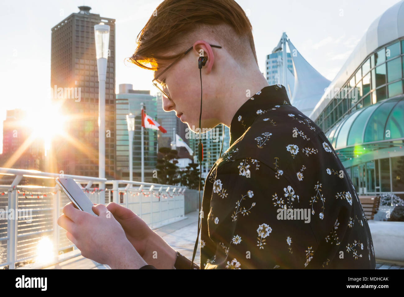 Teenager mit seinem Smart Phone und tragen Ohrstöpsel in Downtown Vancouver, Vancouver, British Columbia, Kanada Stockfoto
