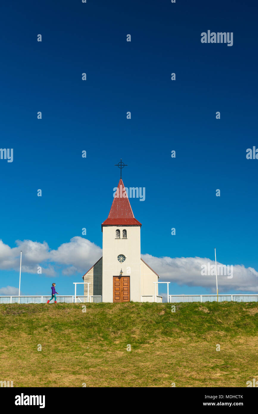 Mädchen zu Fuß vorbei an kleinen Kirche; Langaholt, Island Stockfoto