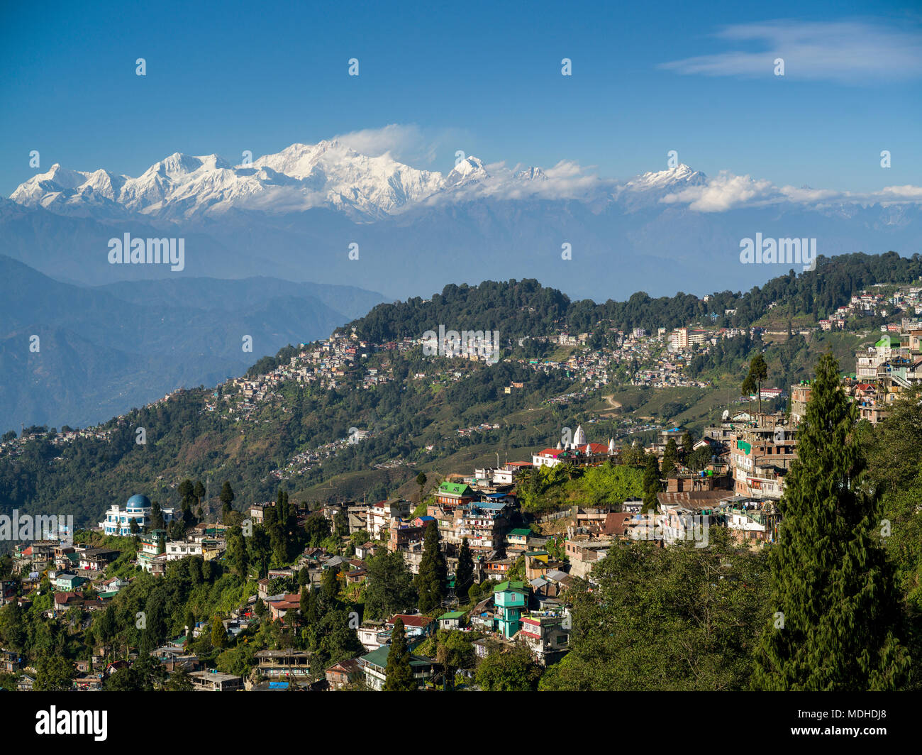Stadt an einem Berghang mit der schroffen, schneebedeckten Gipfel des Himalaya in der Ferne; Darjeeling, West Bengalen, Indien Stockfoto