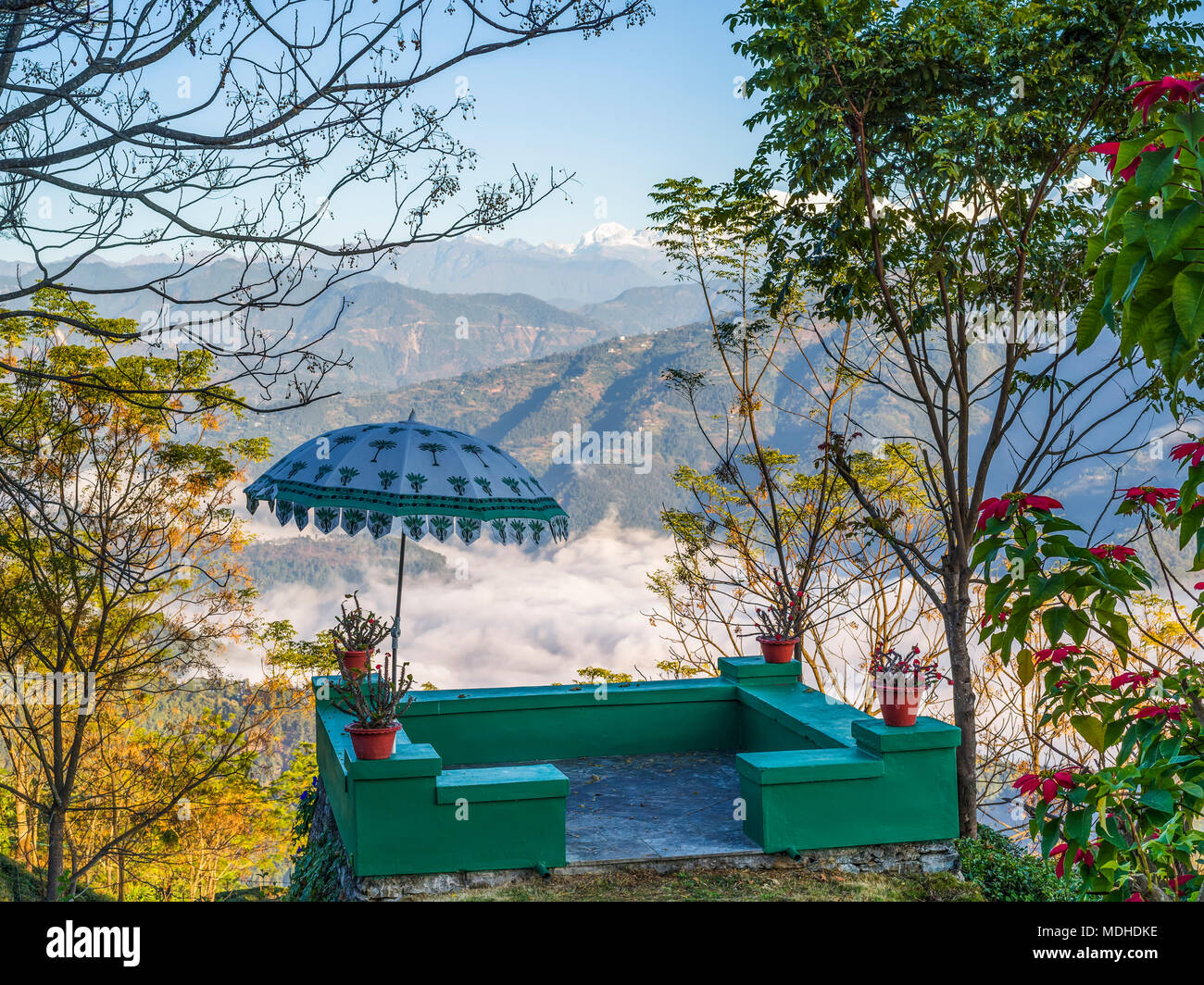 Eine kleine grüne Terrasse mit Sonnenschirm mit Pflanzen dekoriert und mit Blick auf die Berge und das Tal; West Bengalen, Indien Stockfoto
