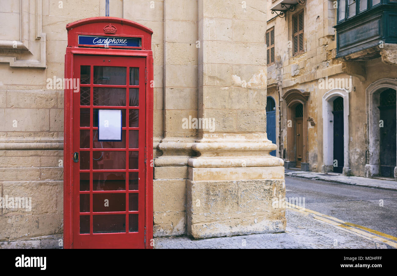 Red Britischen vintage Telefonzelle außerhalb einer Sandsteinfassade Gebäude in Valletta, Malta Stockfoto