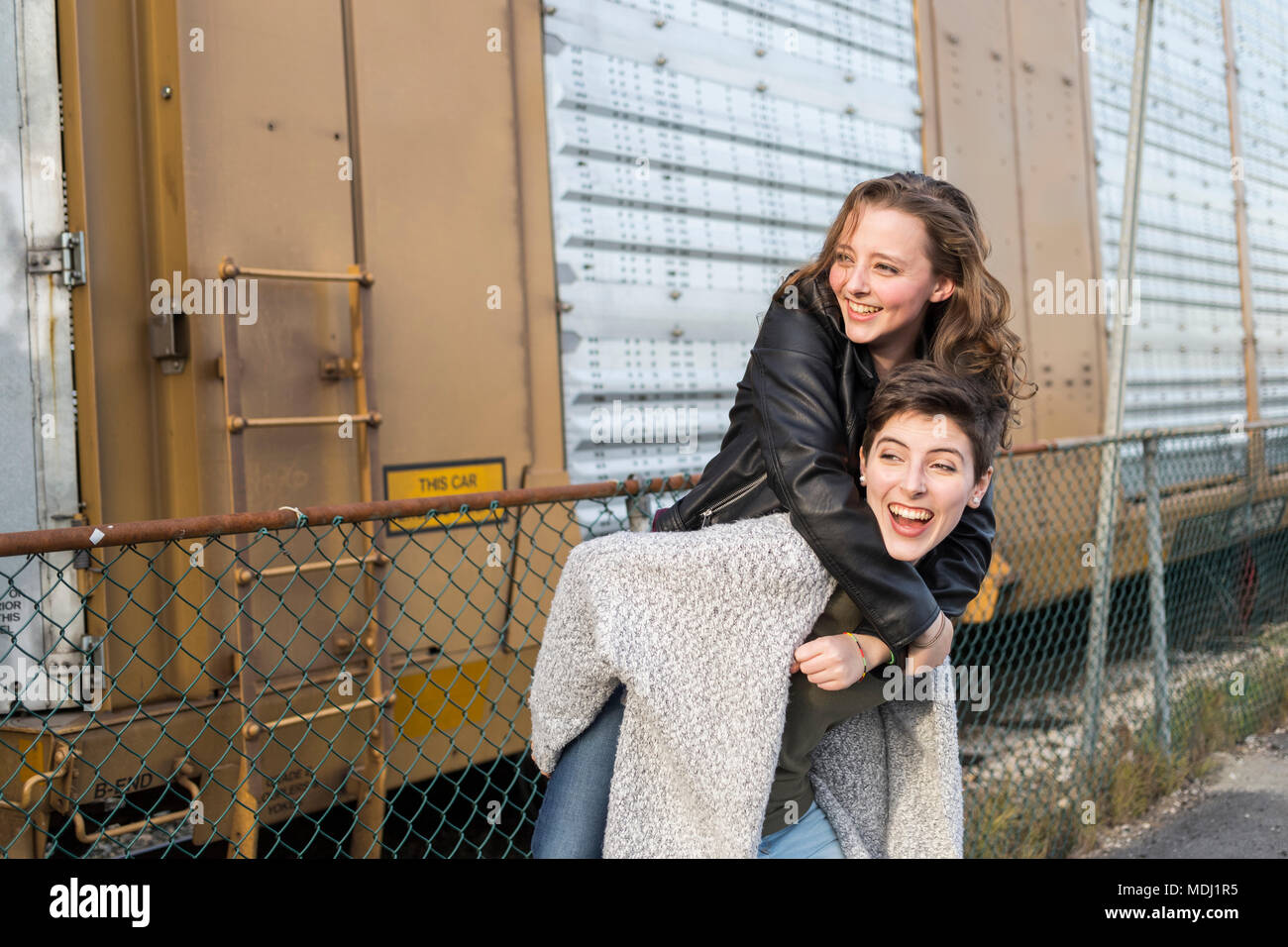Zwei junge Frauen, die in einem spielerischen Pose neben einem Zug Auto; New Westminster, British Columbia, Kanada Stockfoto