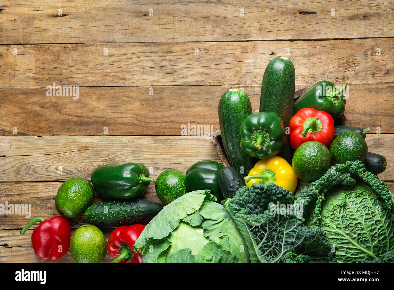 Verschiedene frische organische grünes Gemüse Wirsing Zucchini Gurken rote gelbe Paprika Avocados auf verwitterte Plank Scheune Holz Hintergrund. Überh Stockfoto