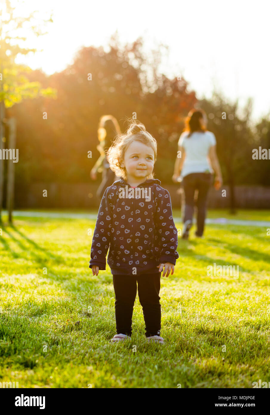 Little Baby Mädchen spielt gerne im Park im Freien im Frühjahr im Gegenlicht. Stockfoto