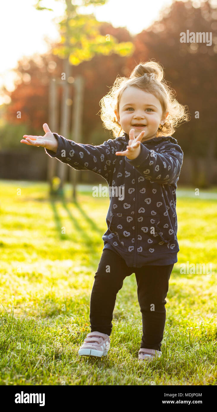 Little Baby Mädchen spielt gerne im Park im Freien im Frühjahr im Gegenlicht. Stockfoto