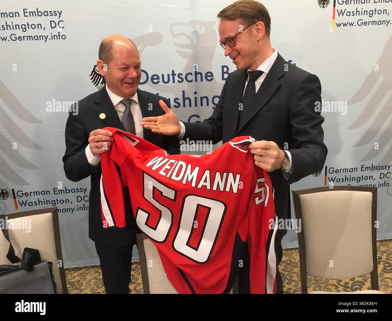 20. April 2018, in den USA, Washington: der deutsche Finanzminister Olaf Scholz (l) von der Sozialdemokratischen Partei (SPD) Hände Jens Weidmann, Präsident der Deutschen Bundesbank, ein Eis Hockey Jersey als Geschenk für seinen 50. Geburtstag. Foto: Georg Ismar/dpa Stockfoto