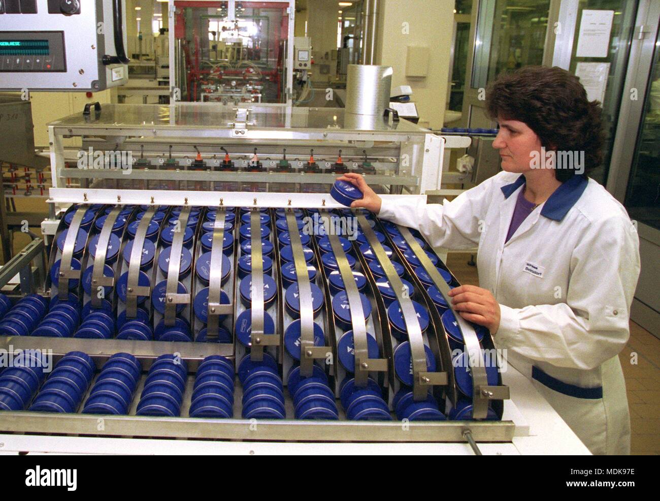 Ein Mitarbeiter der Hamburger Beiersdorf Werk prüft eine Bearbeitungsmaschine mit Nivea Dosen am 21.1.1997. Rund 50 Tonnen des 'creme Classic' werden hier täglich abgefüllt in den blauen Dosen. Rund 11.000 Tonnen die Creme, die fast seit 1911 unverändert produziert worden ist, sind in Hamburg, das ungefähr 60% des weltweiten Füllmenge produziert. Die universelle Creme wird heute in rund 160 Ländern auf der ganzen Welt zur Verfügung. Der Name des Erfinders, der Apotheker Oscar Troplowitz, wurde aus dem Namen abgeleitet, weil die Farbe von dem lateinischen Wort für Schnee weiß, niveus. | Verwendung weltweit Stockfoto
