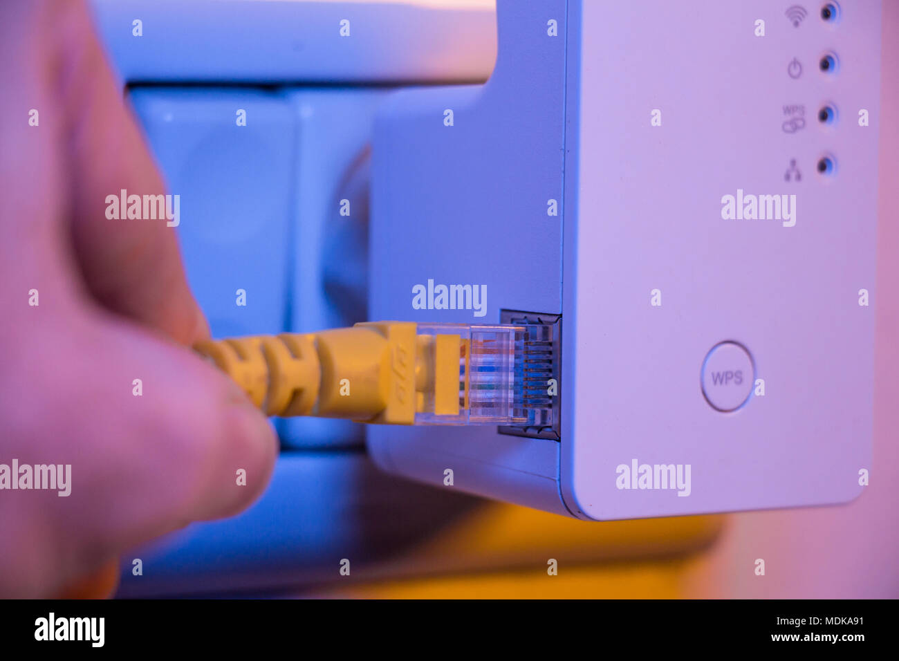Man Ethernet-Kabel in WiFi Extender gerät das in der Steckdose an der Wand ist. Das Gerät ist im Access Point Modus, die helfen, zu verlängern. Stockfoto