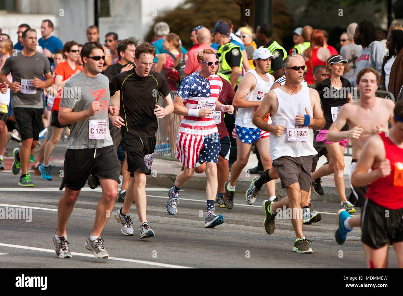 Ein Läufer in Sterne und Streifen von Kopf bis Fuß gekleidet, läuft auf die Ziellinie an der Peachtree Road Race am 4. Juli 2014 in Atlanta, GA. Stockfoto