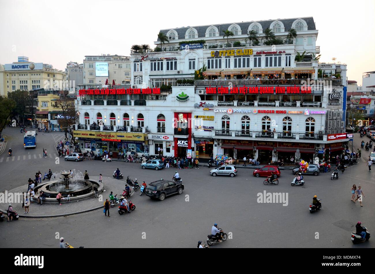 Alte Gebäude aus der Kolonialzeit und dem Kreisverkehr und Verkehr, einschließlich Fußgänger mit Fast-Food-Restaurants Hanoi's Old Quarter Vietnam Stockfoto