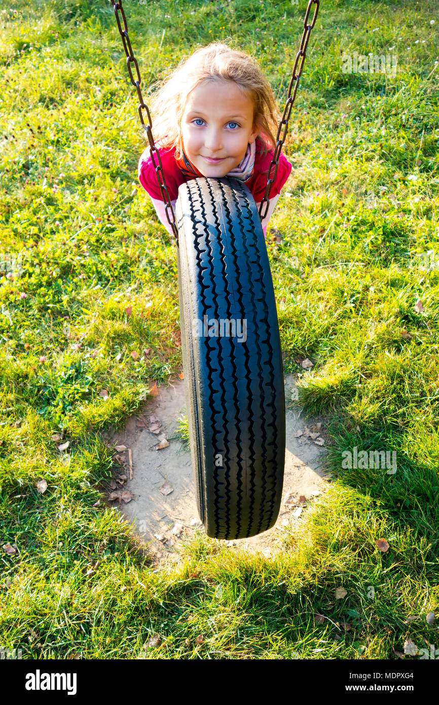 Junge Mädchen im Herbst park Spaß auf dem Reifen schwingen. Stockfoto