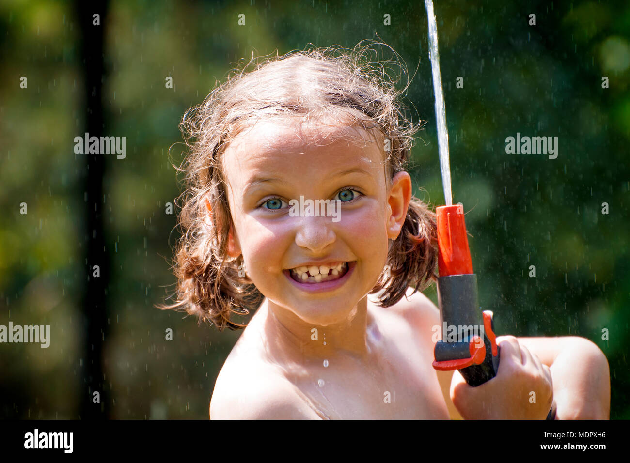 Junge Mädchen Spaß haben, während sie unter Garten Sprinkler im heißen Sommer Tag stehen. Stockfoto