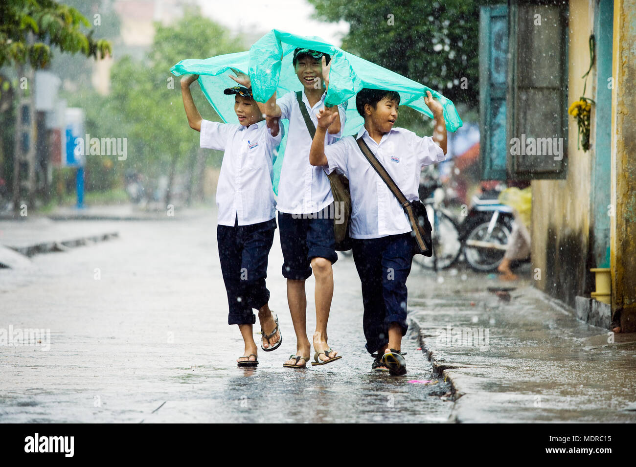 Hoi An, Vietnam; Jungen Schutz vor einem Regenguss in der Regenzeit Stockfoto