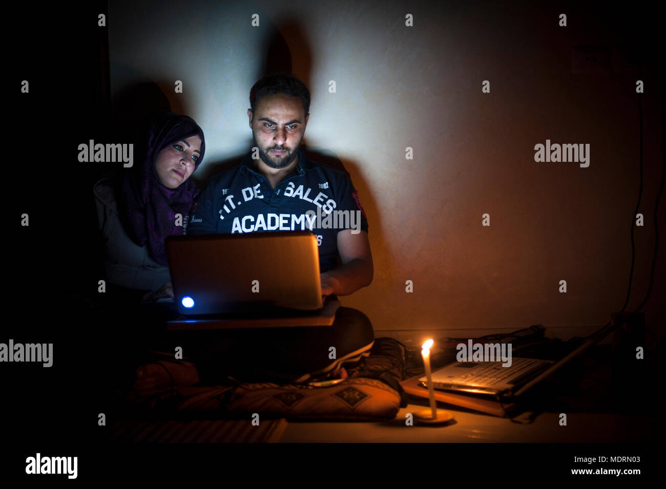 IT-Spezialisten Mohammad und Tala Al-Nagi versuchen zu Hause durch einen Stromausfall in Gaza mit der Restkapazität der Batterie in Ihrem Laptop Computern zu arbeiten. Stockfoto