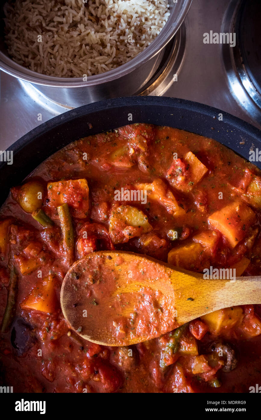 Das Kochen von Essen. Ein gemischtes Gemüse Curry und eine Pfanne mit braunem Reis Stockfoto