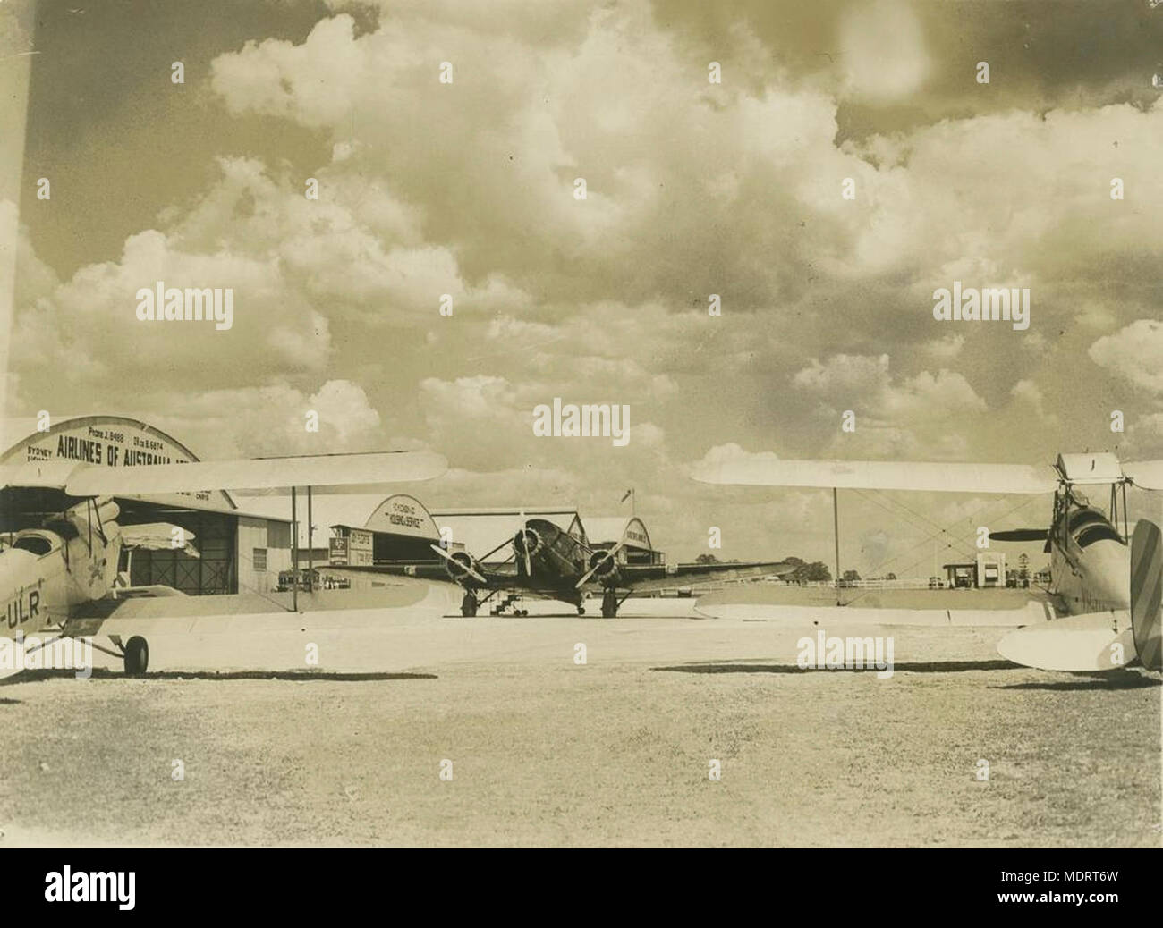 Flugzeug auf der Rollbahn am Archerfield, Brisbane, ca 1936. Lage: Brisbane, Queensland, Australien Beschreibung: Mehrere Flugzeuge werden geparkt auf dem Asphalt und hangars sind im Hintergrund sichtbar. Eines der Flugzeuge hat eine Registrierung UHH. Dies ist das Flugzeug, das auf dem Lamington Plateau 1937 abgestürzt. Stockfoto