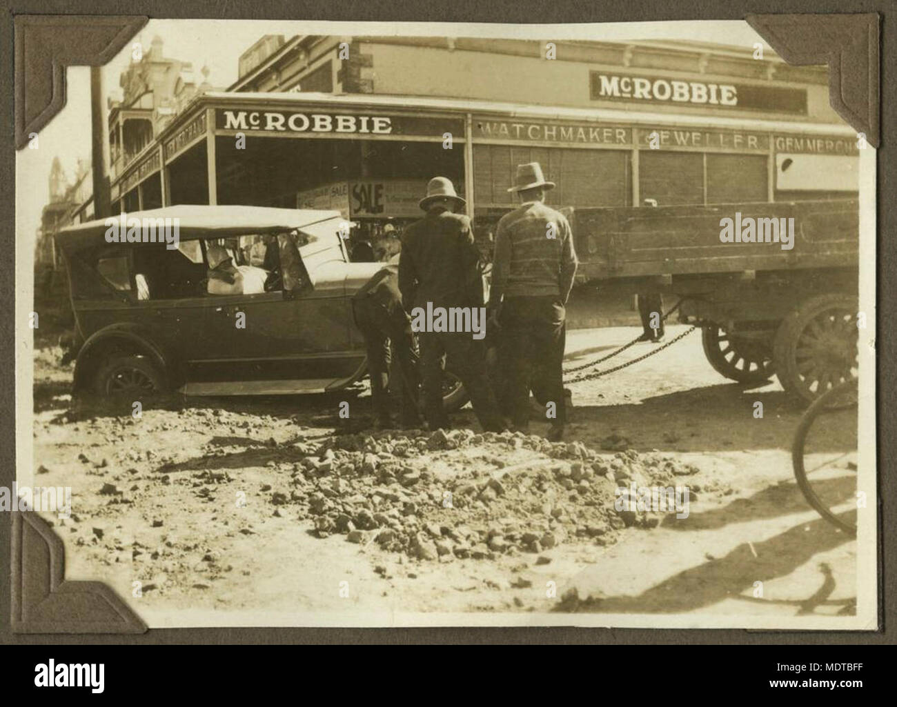 Große cabrio Touring Car versunken in der Bundaberg Street, 1929. Lage: Bundaberg, Queensland Beschreibung: nasses Wetter im Winter Moore ein Auto an der Ecke der Bourbon und Targo Straßen in Bundaberg. McRobbie Juweliere ist hinter dem Auto. Die weiblichen Fahrer trägt einen cloche Hut. Stockfoto