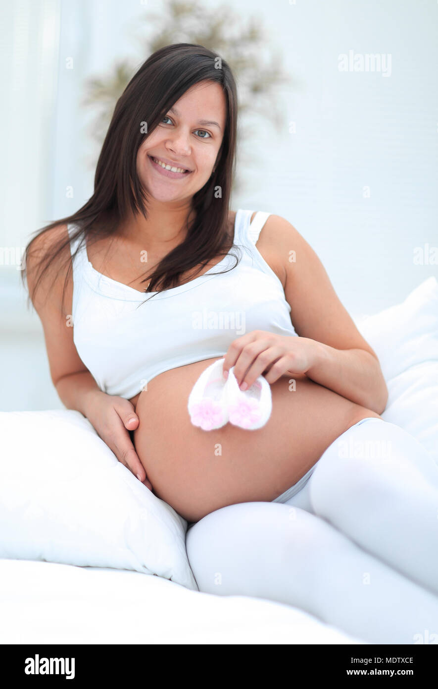 Schöne schwangere Frau im Wohnzimmer sitzen. Stockfoto