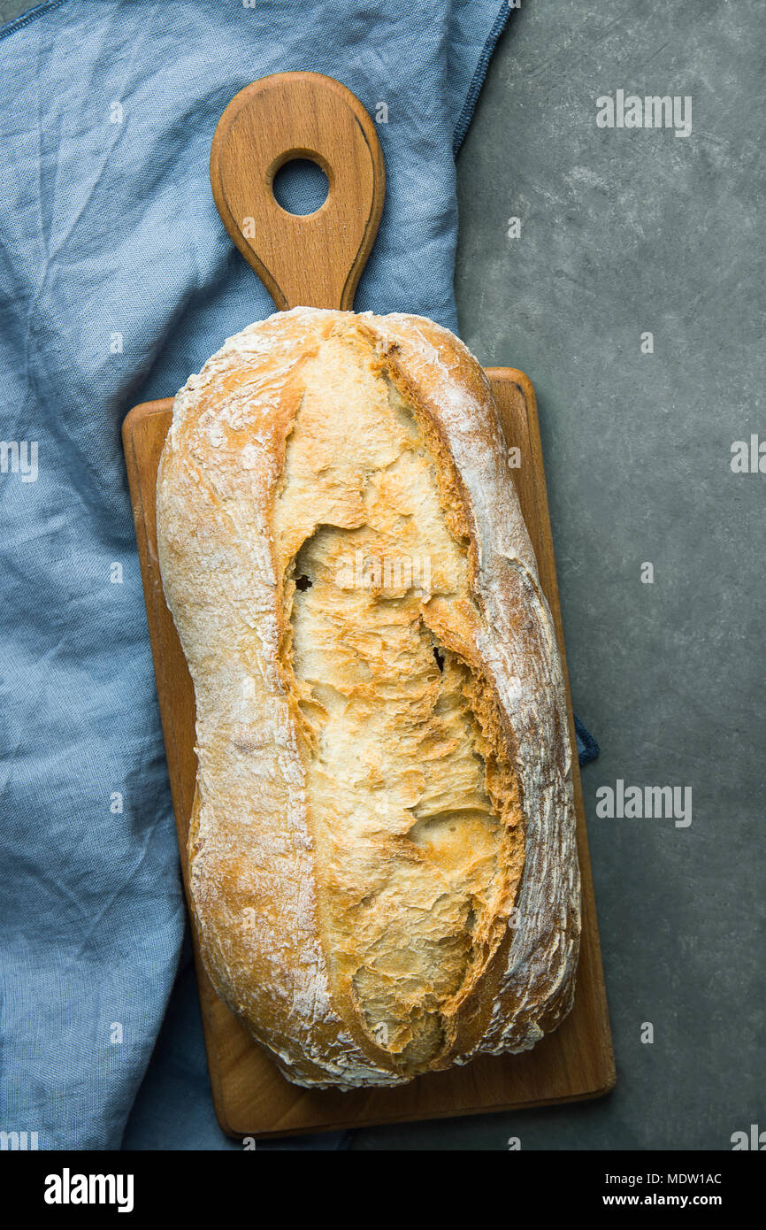 Frisch gebackene Handgefertigte Rustikales Brot Laib auf Schneidebrett dunklen Stein Hintergrund. Authentische rustikalen Stil. Lifestyle. Mediterrane Küche. Essen Ba Stockfoto