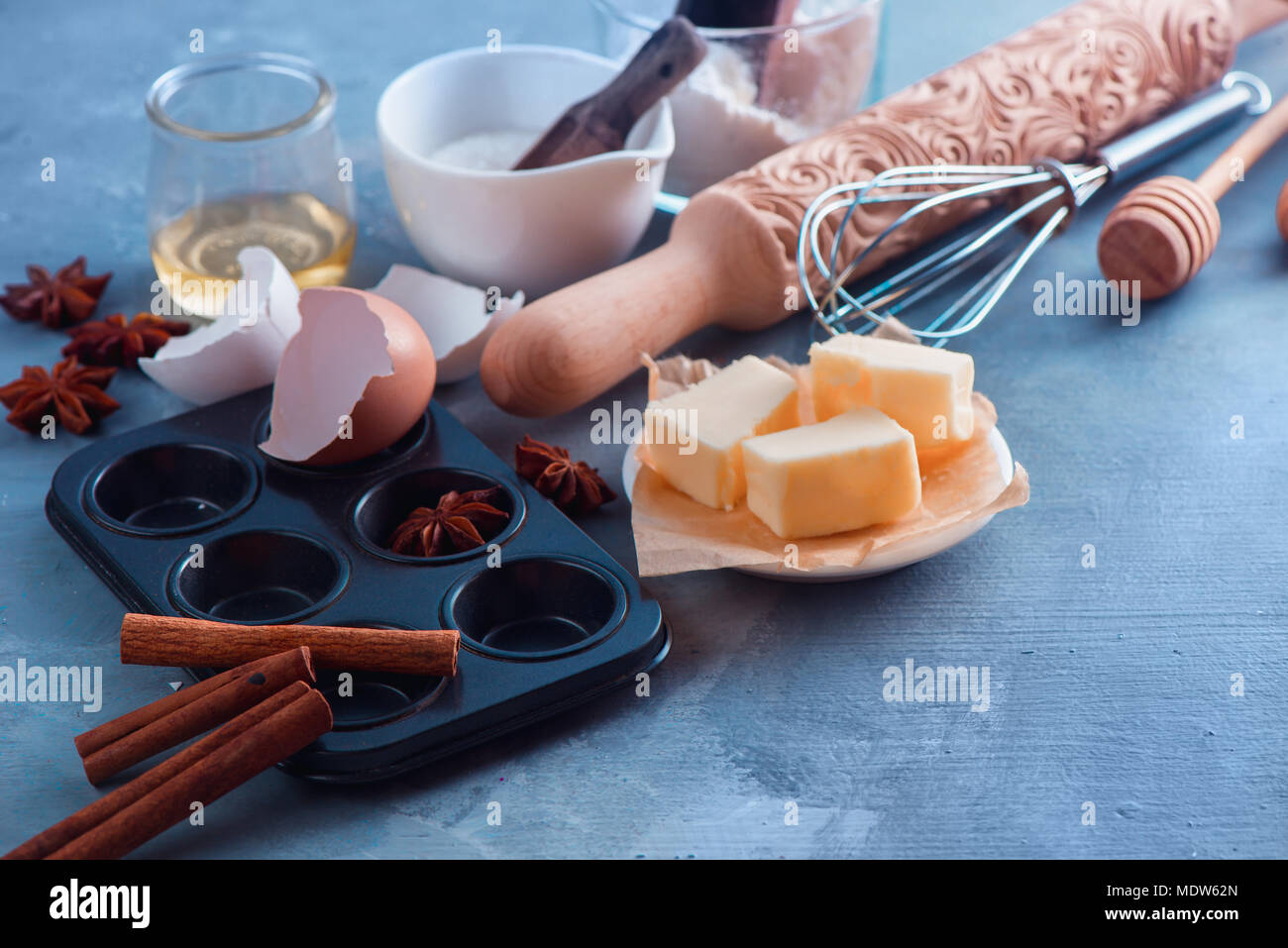 Kochen Konzept mit Backen Werkzeuge und Zutaten. Ein nudelholz, Honig Löffel, ein Muffin Tin, ein Schneebesen, Mehl, buter und Eierschale auf einen konkreten Hintergrund mit kopieren. Stockfoto