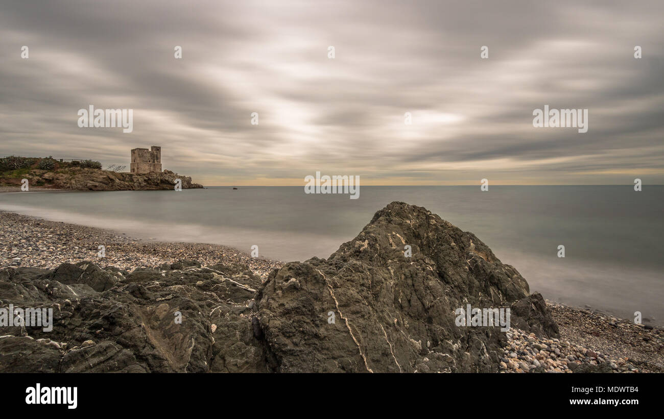 Eine lange Exposition von Torre de la Sal & Felsen unter einem dramatischen Himmel an der Südküste von Spanien. Stockfoto