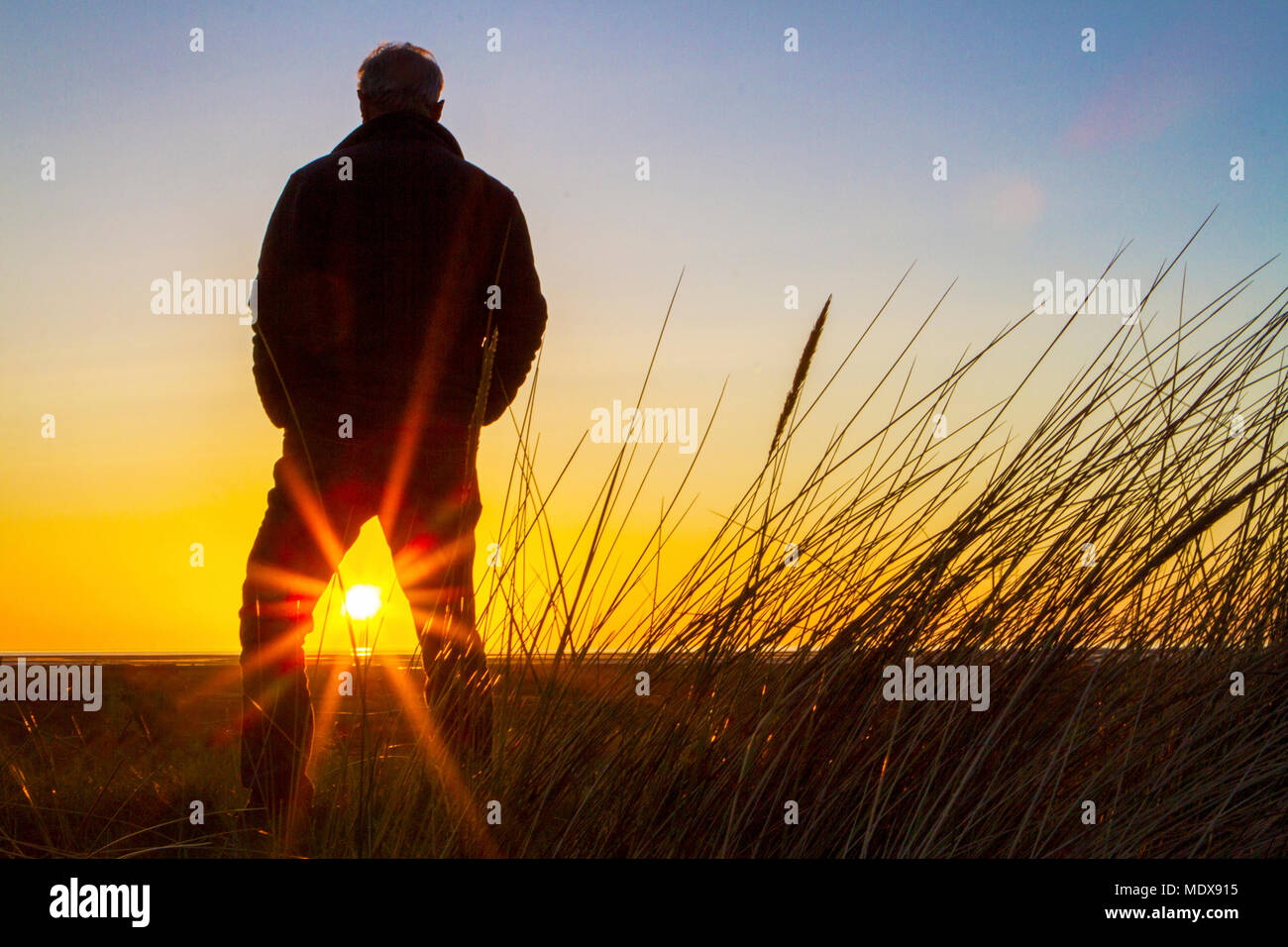 Atemberaubenden Sonnenuntergang, Southport, Merseyside. April 2018 20. UK Wetter. Ein Mann steht auf den Sanddünen beobachten wie der Sonnenuntergang in den Horizont über Southport Strand fällt in Merseyside. Credit: cernan Elias/Alamy leben Nachrichten Stockfoto