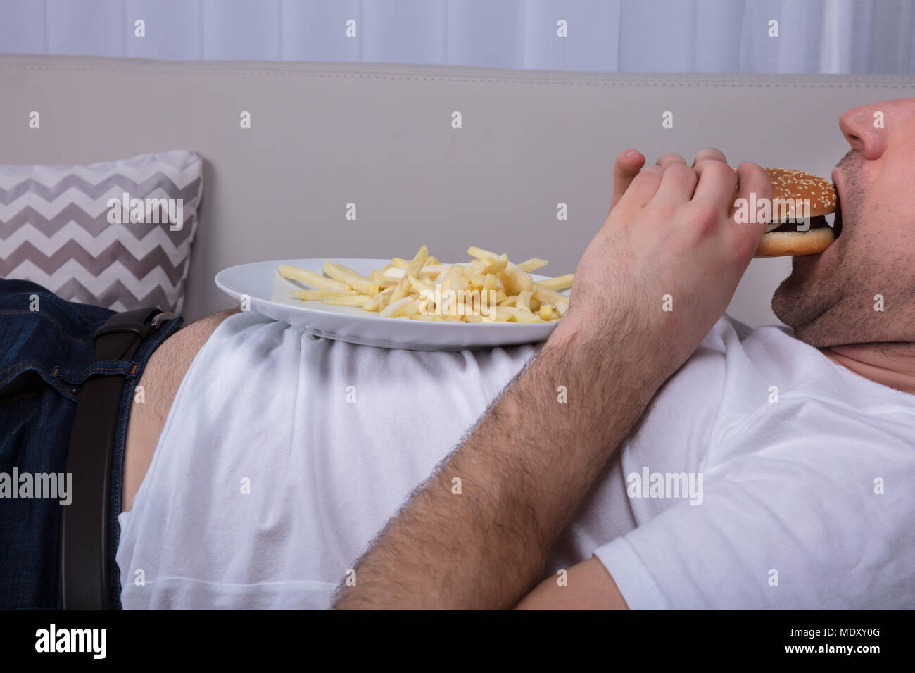 Nahaufnahme von einem Mann essen Burger und Pommes Frites auf Platte Stockfoto