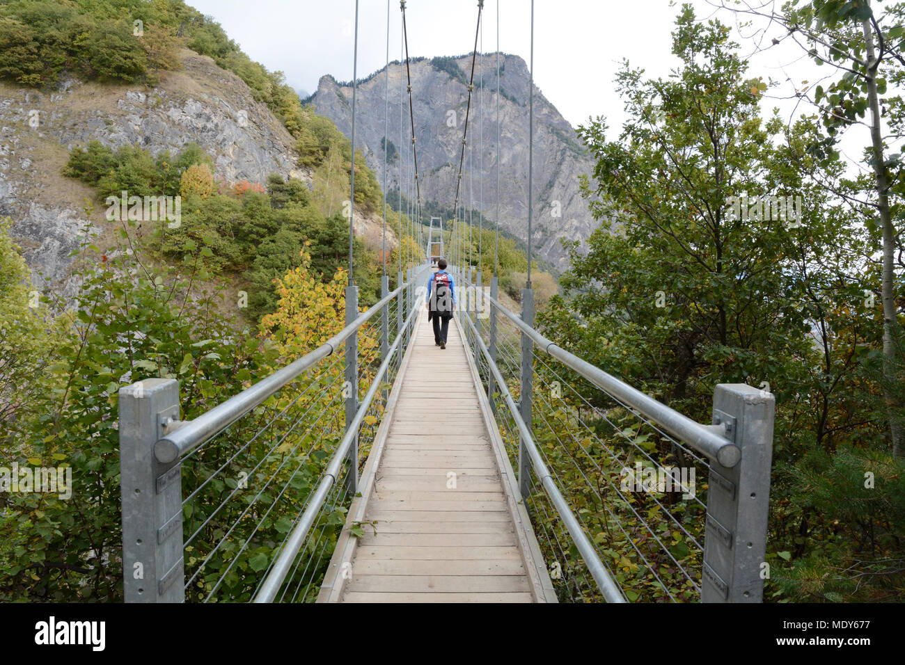 Eine Frau wandern entlang einer Brücke auf der Swiss Wine Trail in den Ausläufern der Berner Alpen, in der Nähe von Leytron, im Kanton Wallis, Schweiz. Stockfoto