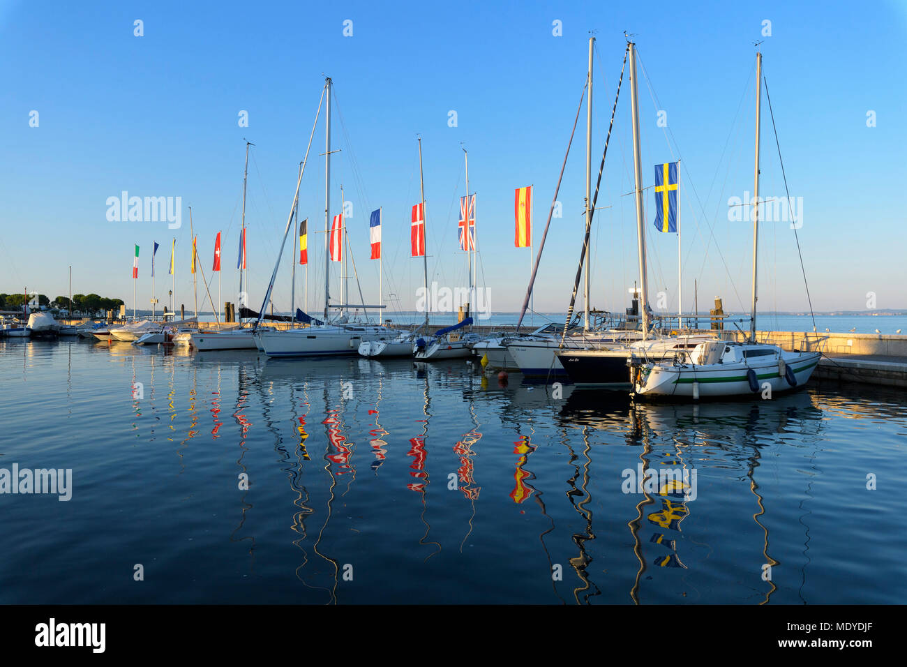 Reihe von Booten und bunte Europäische Flaggen im Hafen Marina am Gardasee (Lago di Garda) in Bardolino in Venetien, Italien Stockfoto